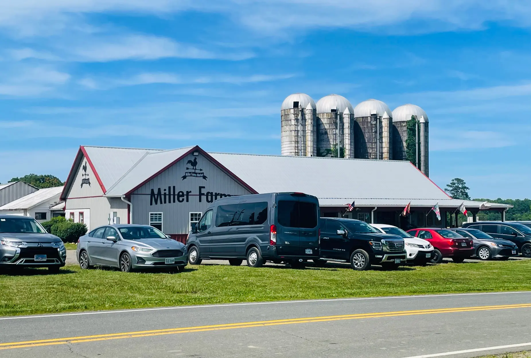 Farm building with parked cars and silos.