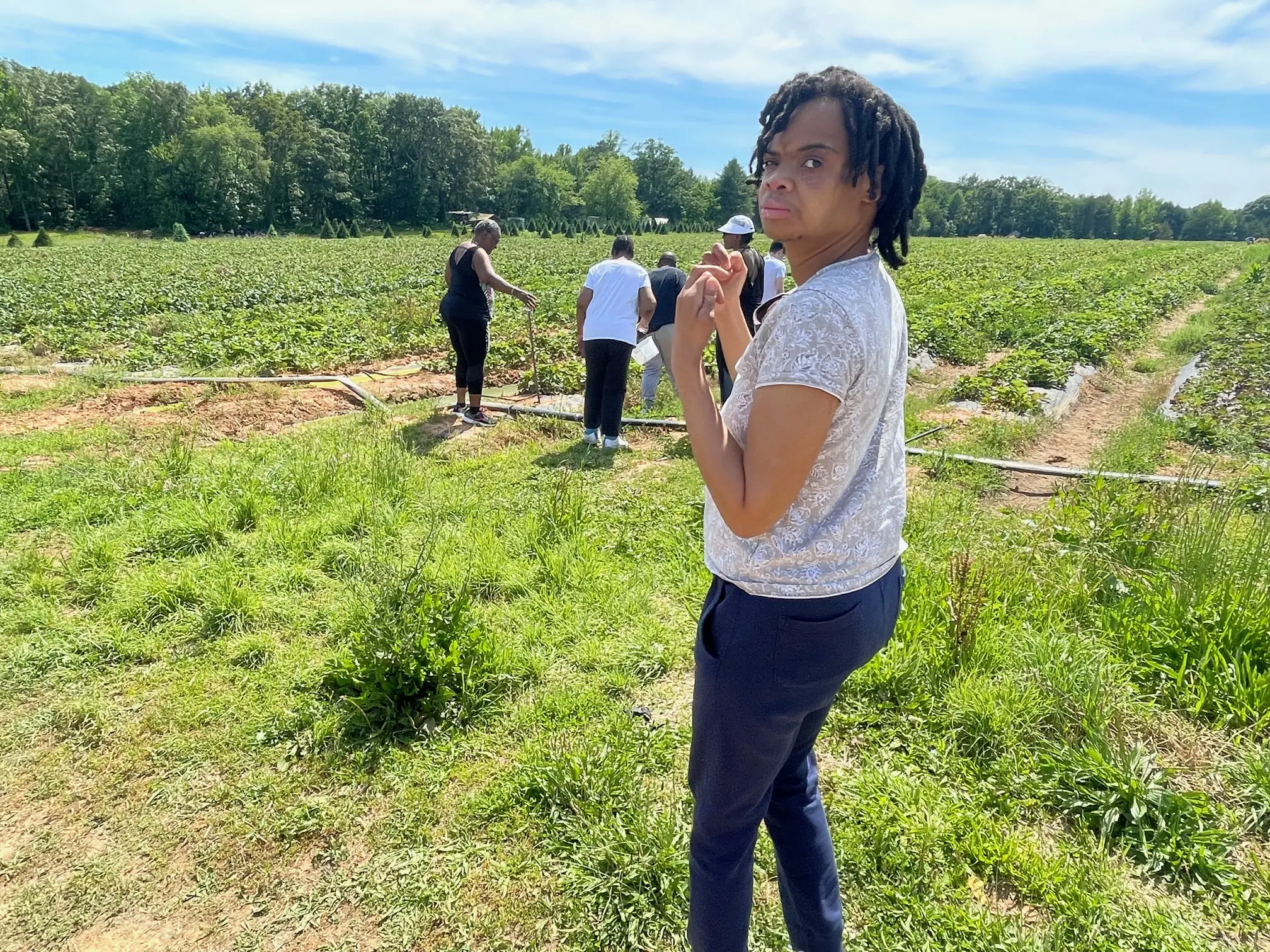 Person standing in field with others nearby.