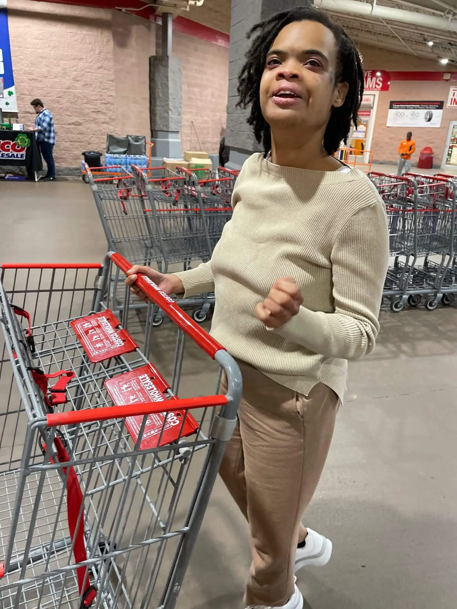 Person pushing a shopping cart in a store aisle.