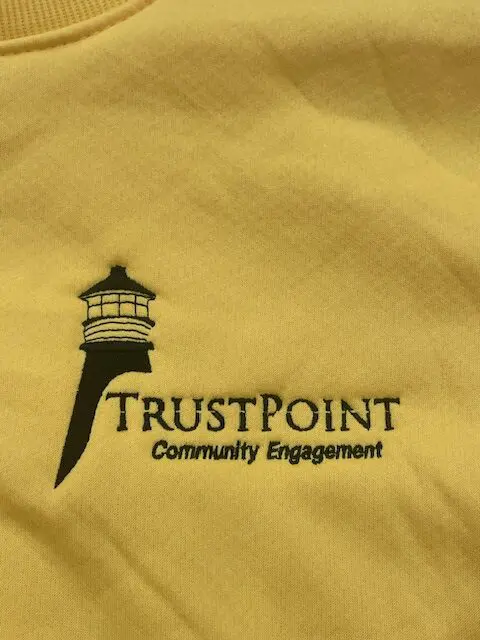 Logo of TrustPoint Community Engagement with a lighthouse design.