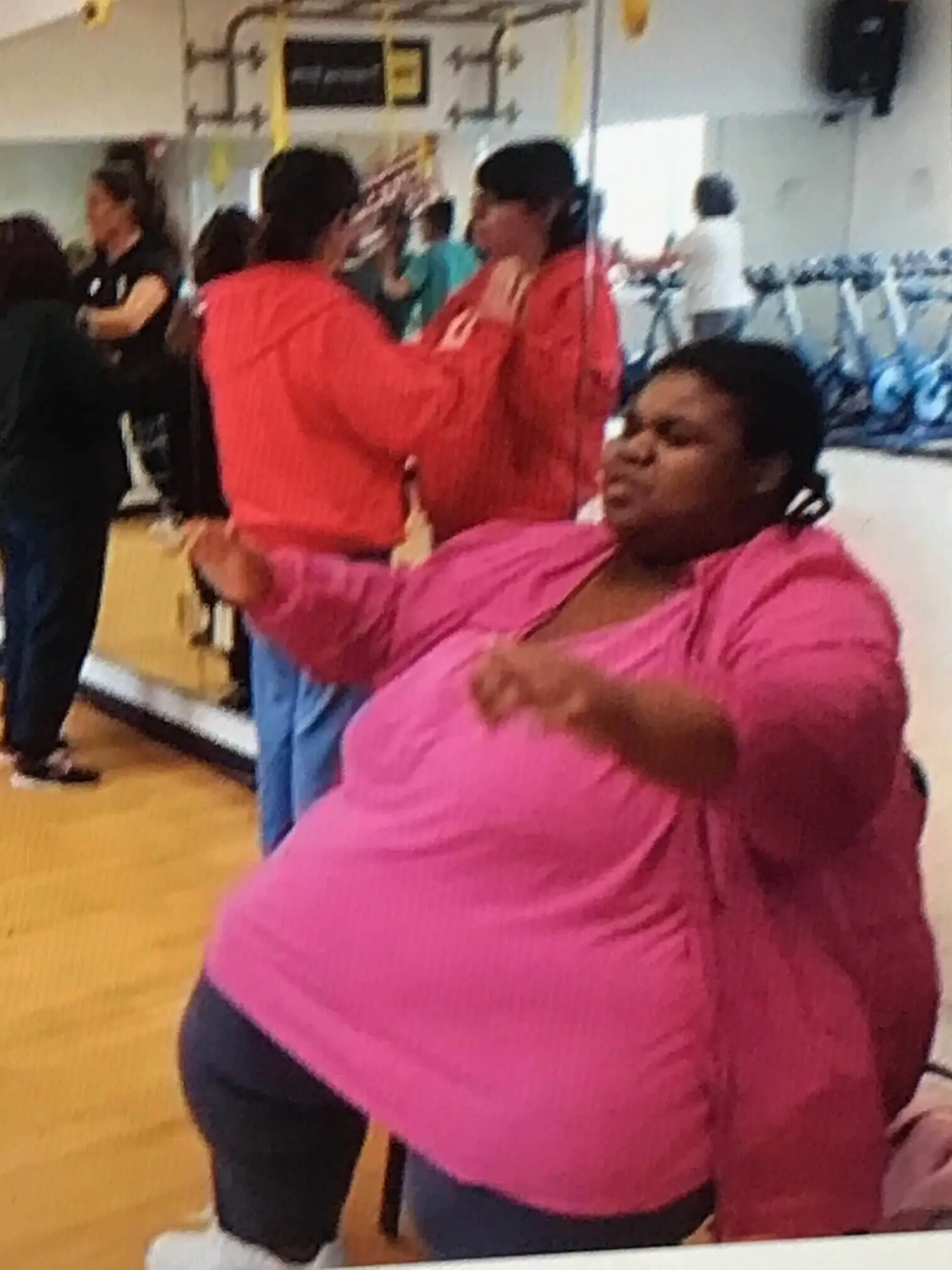 Woman in a pink shirt dancing with enthusiasm indoors.