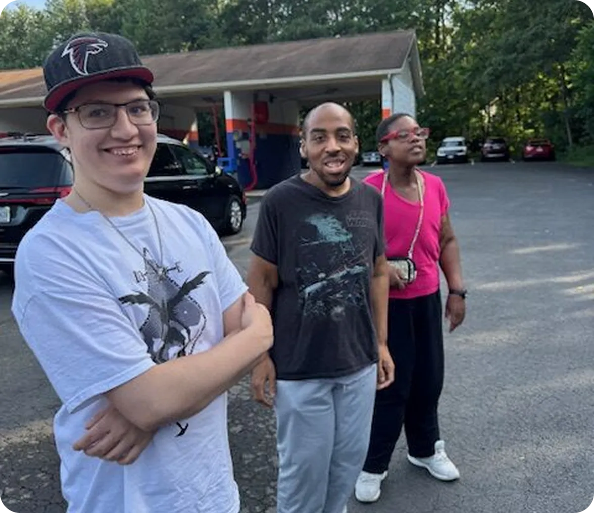 Three people smiling in a parking lot.