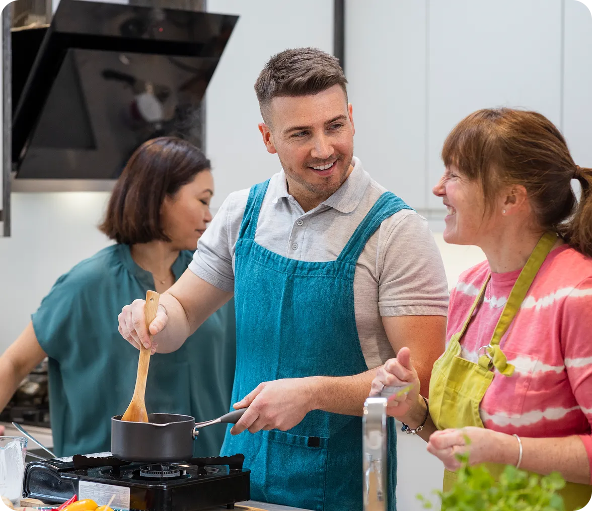 People cooking together in a kitchen, smiling.