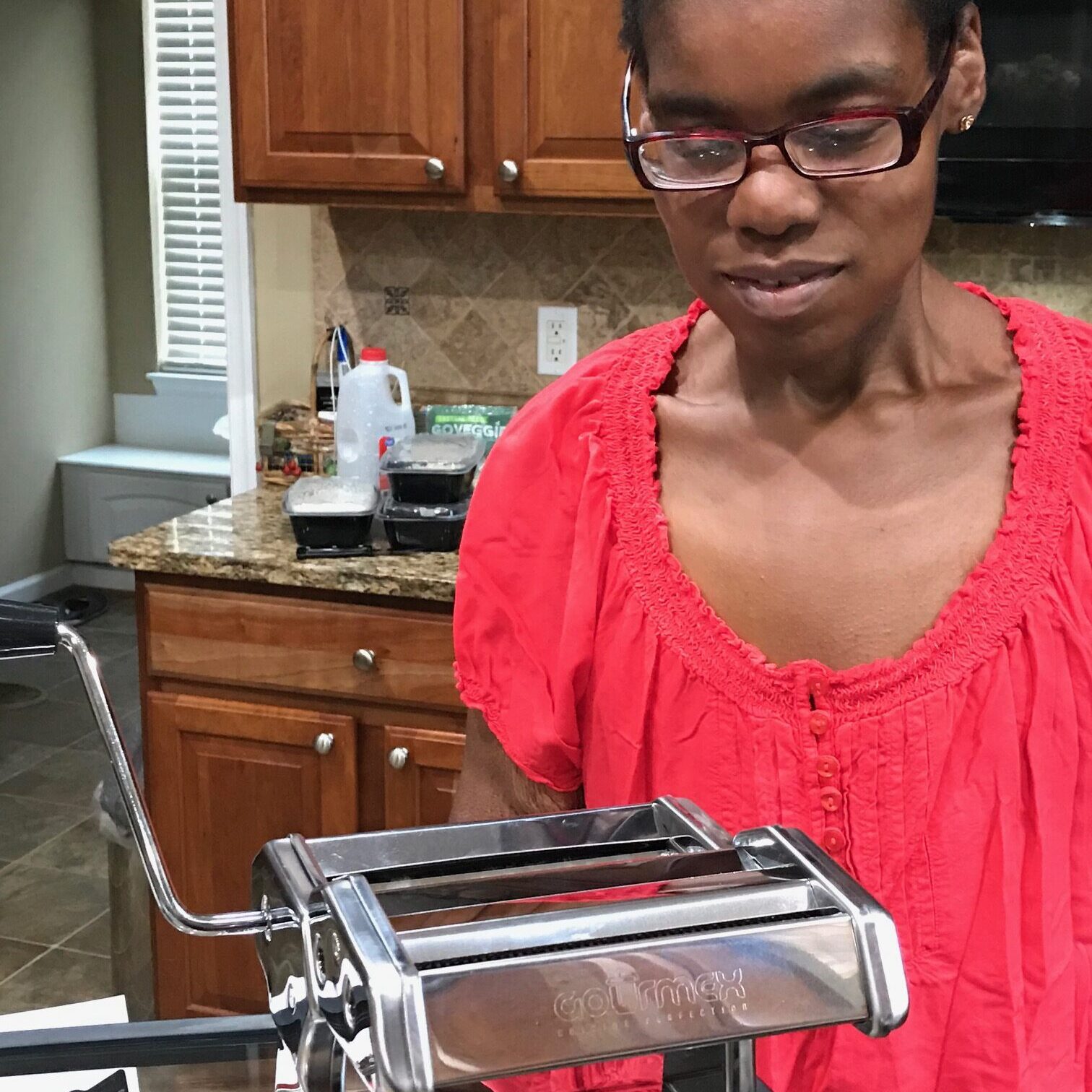 Woman using a pasta maker in a kitchen.