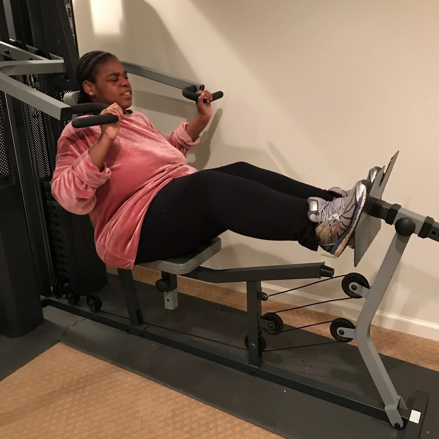 Person using a leg press machine indoors.