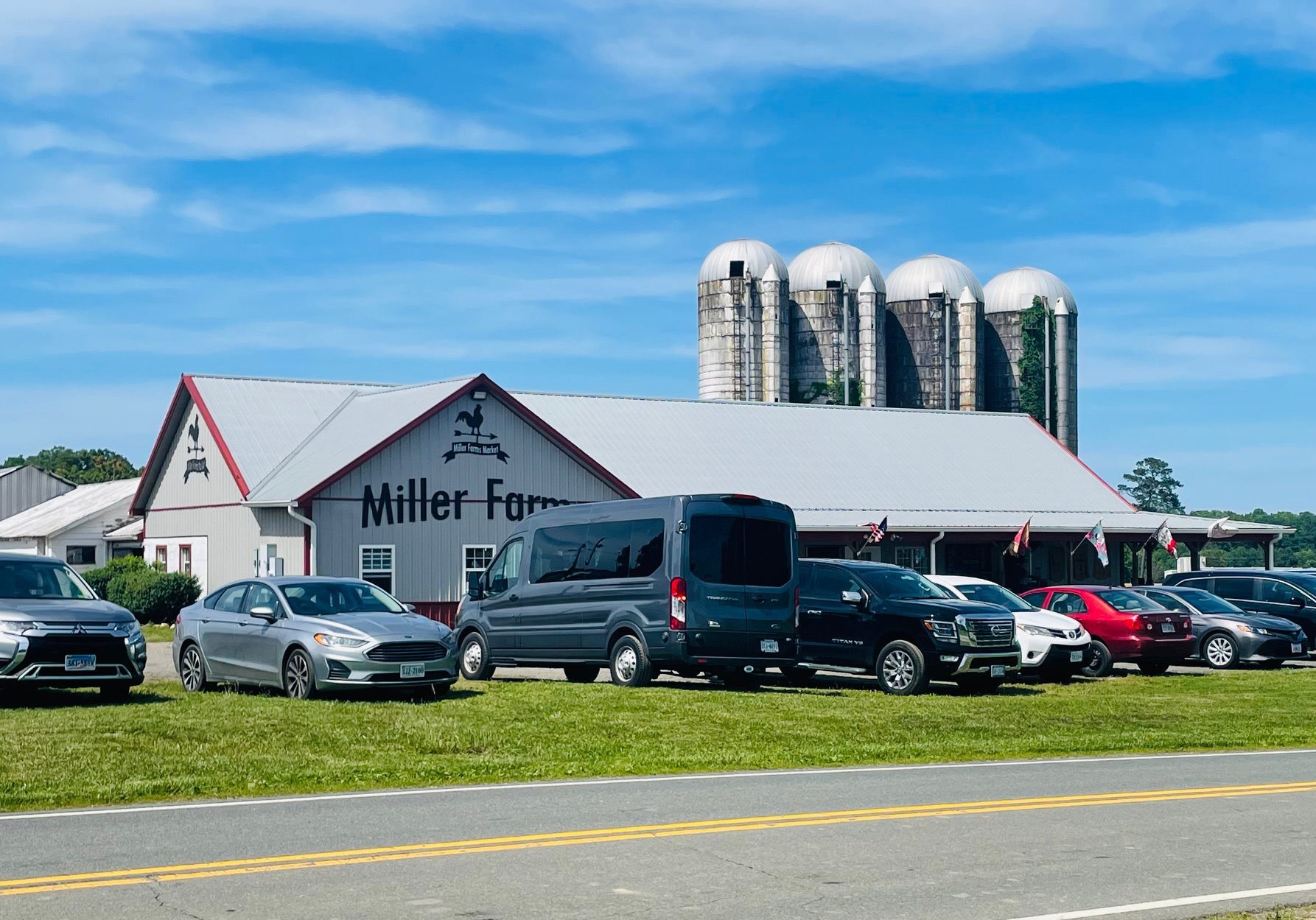 Farm building with parked cars and silos.