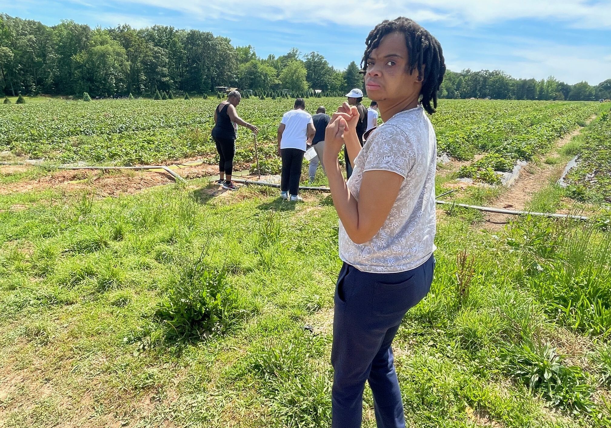 Person standing in field with others nearby.