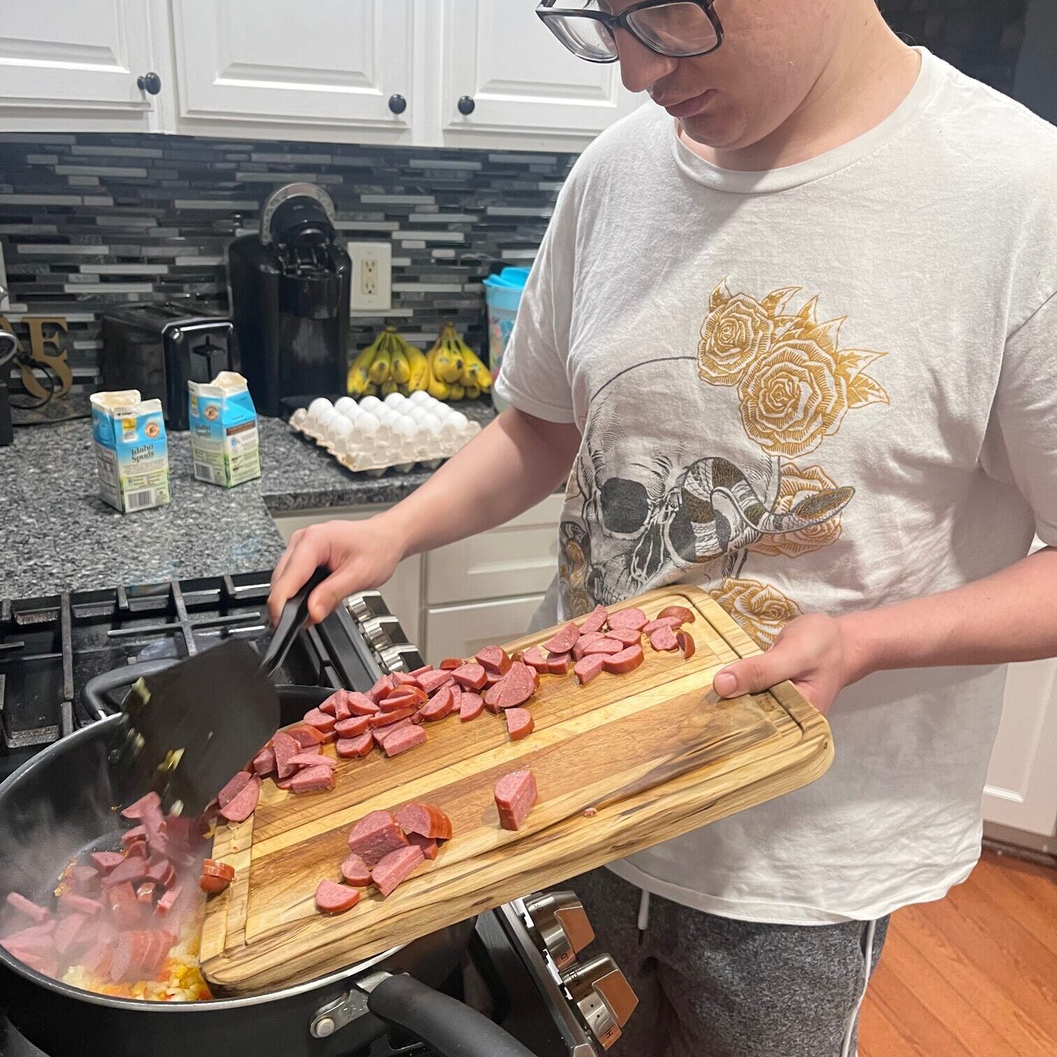 Person cooking sausages in kitchen.